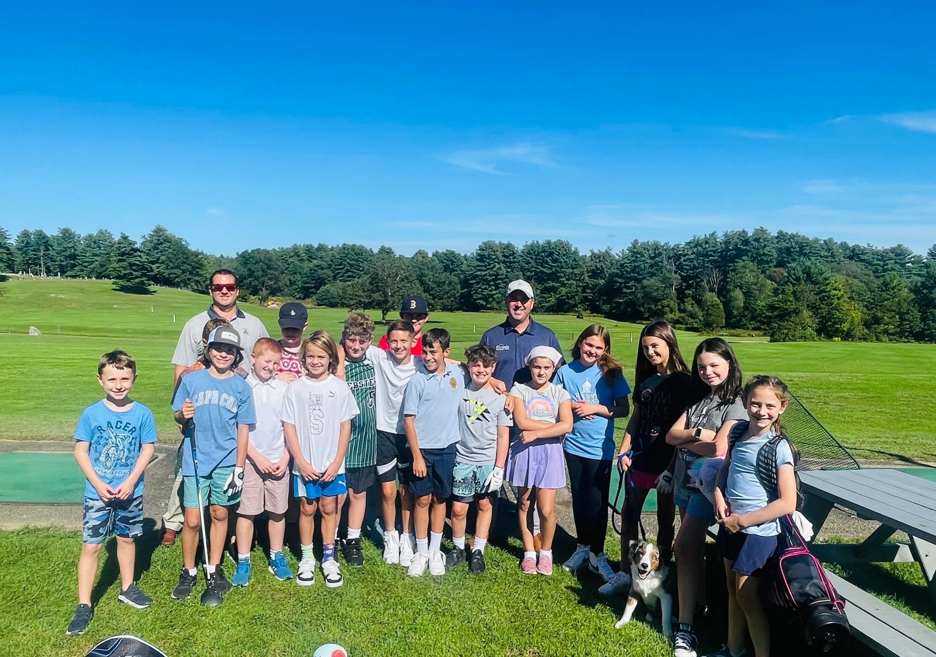 A group of children are posing for a picture in a grassy field.