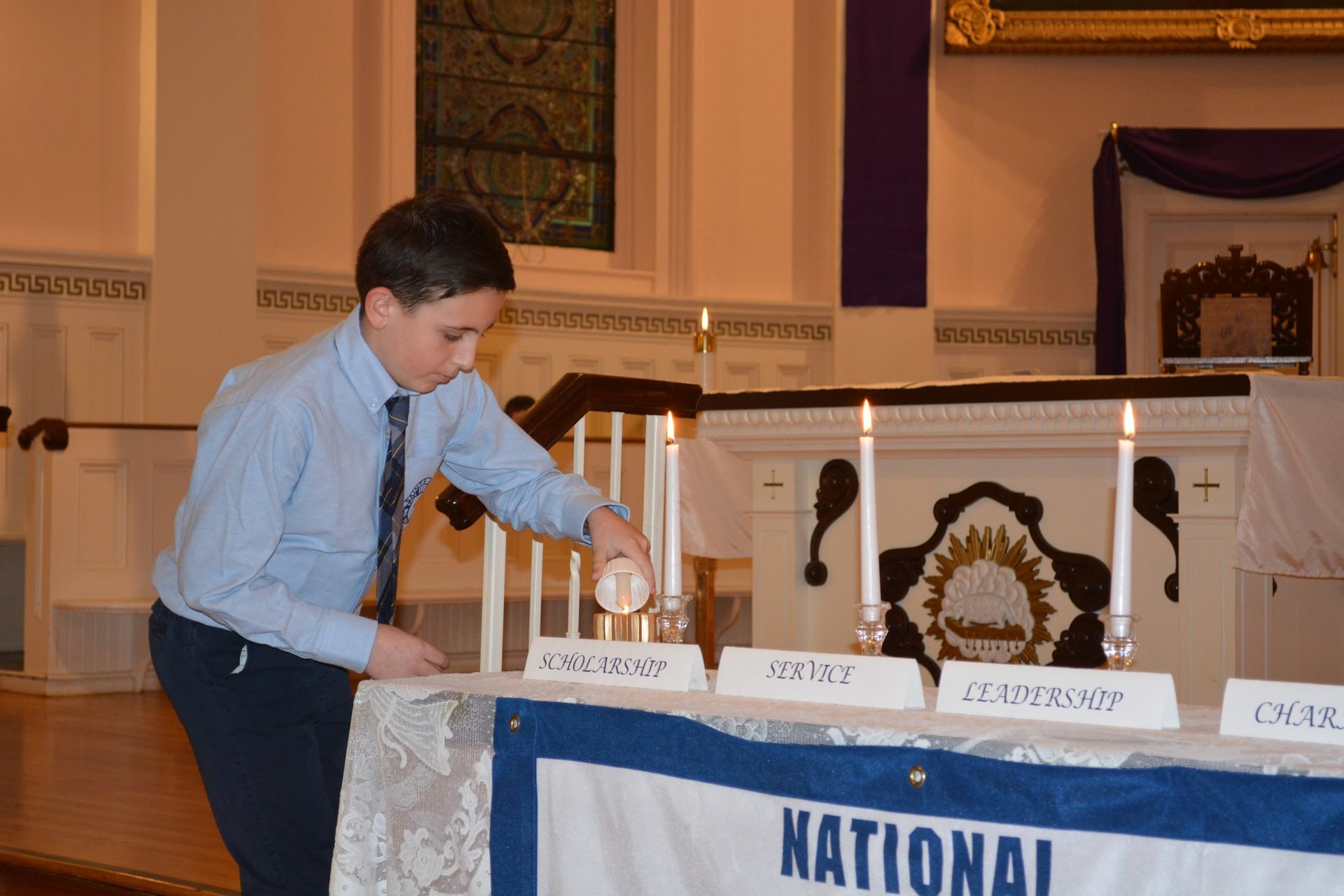 A boy lighting candles in front of a national banner