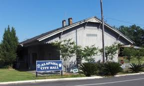 Alapaha City Hall, a gray wooden building with a sign on a sunny day.