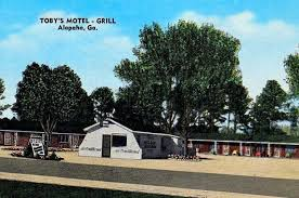 Toby's Motel and Grill in Alapaha, GA, with a one-story building and motel rooms, trees, and a clear sky.