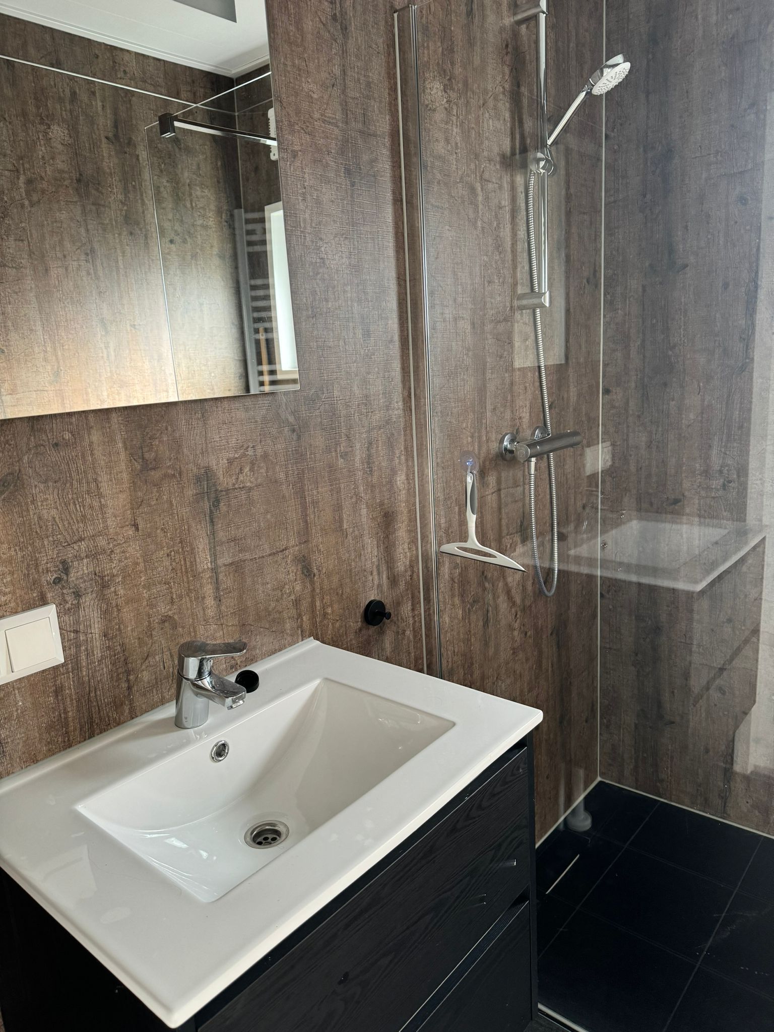 Een badkamer met wastafel, spiegel en douche.