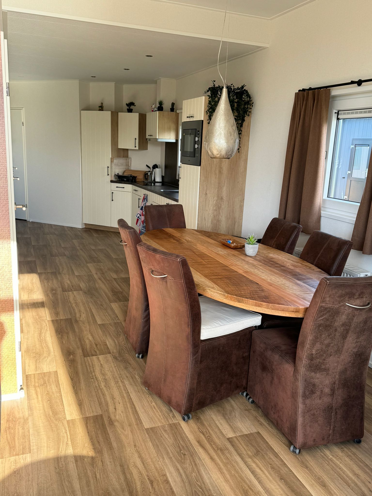 Een eetkamer met een houten tafel en bruine stoelen.