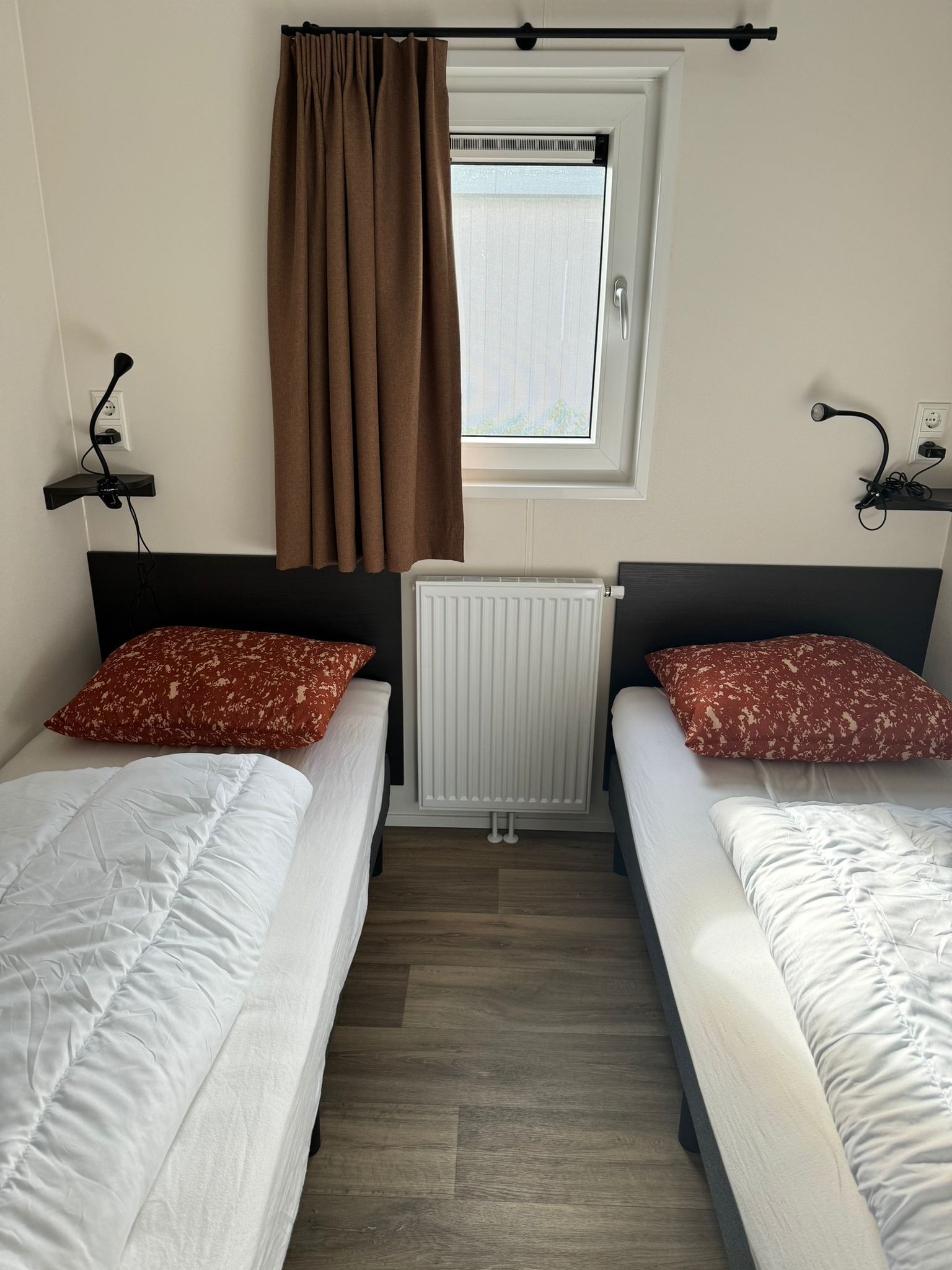 Een slaapkamer met twee bedden en een raam