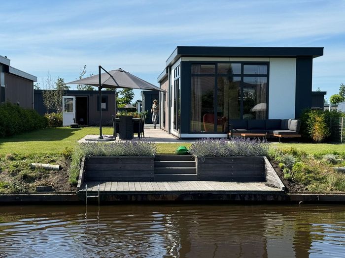 Een huis ligt naast een watermassa met een steiger ervoor.