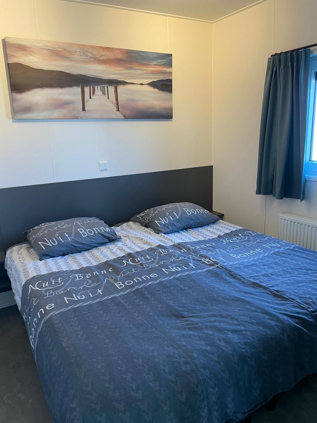 Een slaapkamer met twee bedden en een schilderij aan de muur boven het bed.