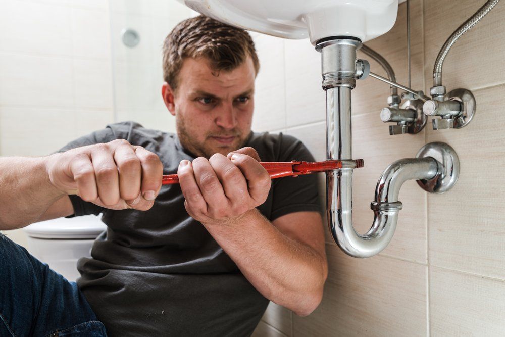 Man Tightening the Pipe Under the Sink — Rancho Cucamonga, CA — Advanced Plumbing Solutions