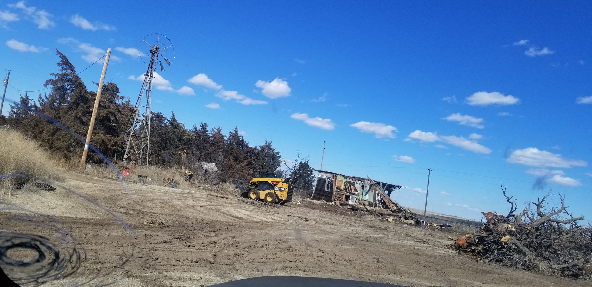 Yellow brush cutter clearing bushes in a wooded area.