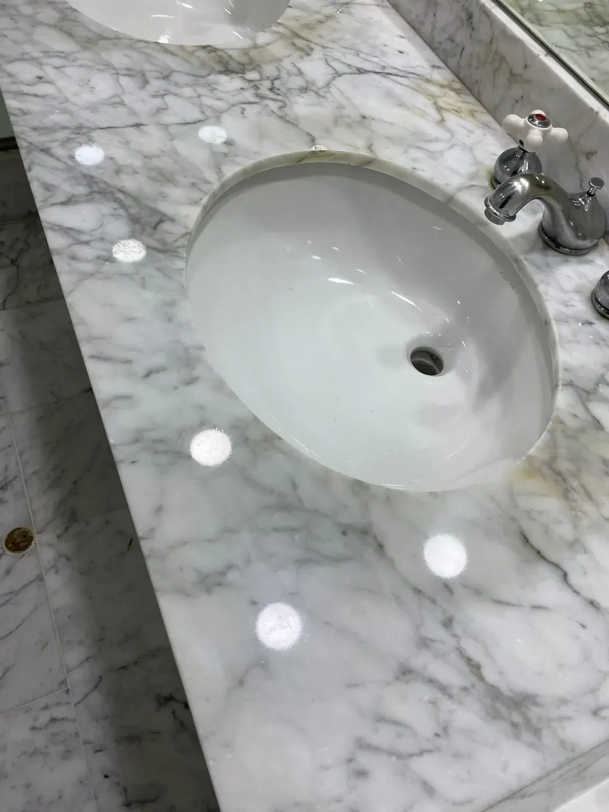 White oval sink in marble countertop with chrome faucet.