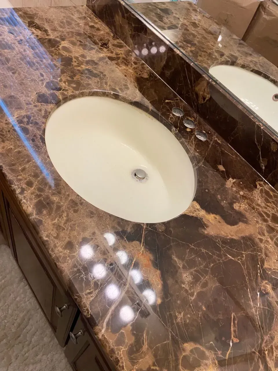 Bathroom vanity with oval sink, brown marble countertop, and chrome fixtures.