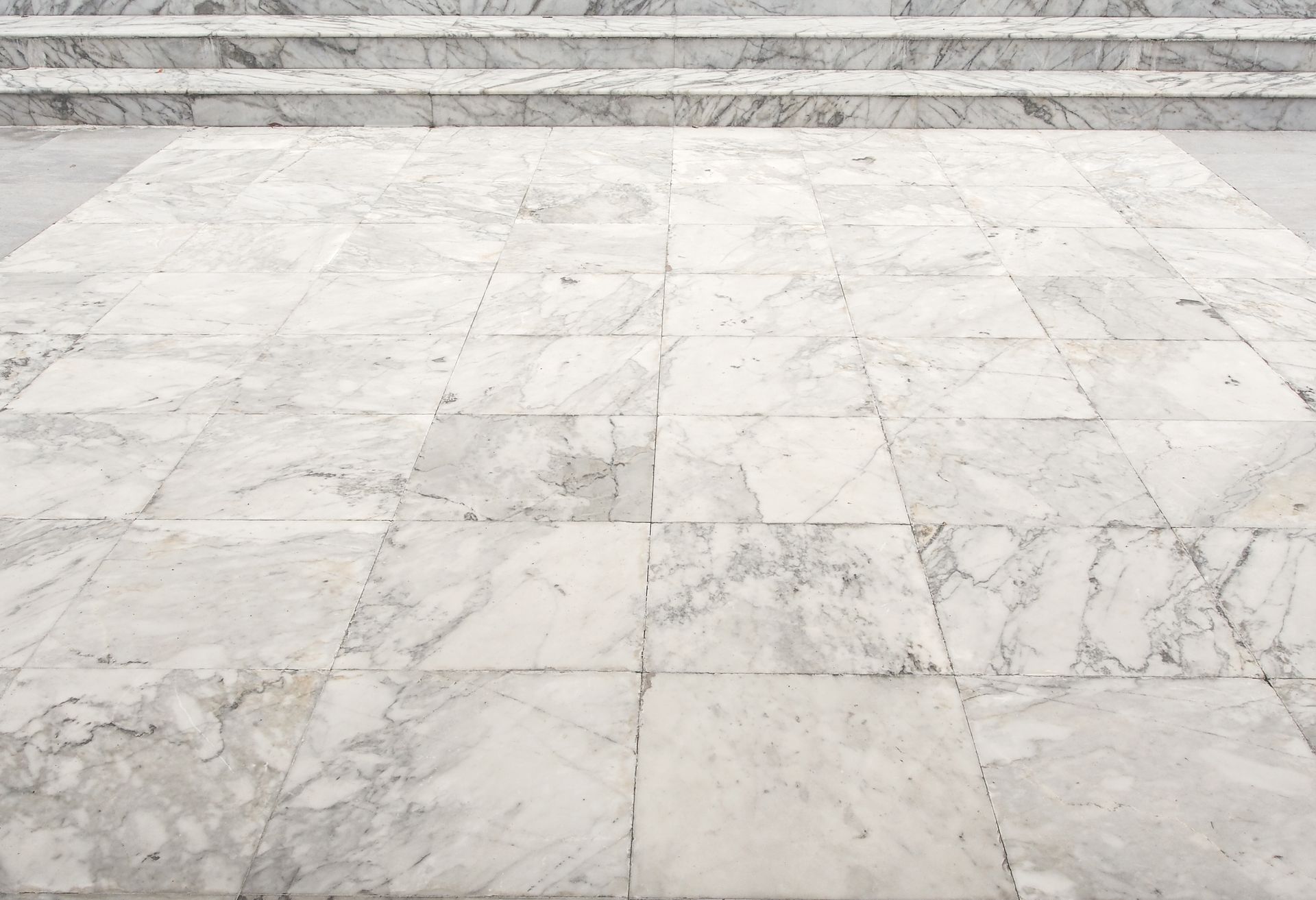 White marble tiled floor leading to steps.