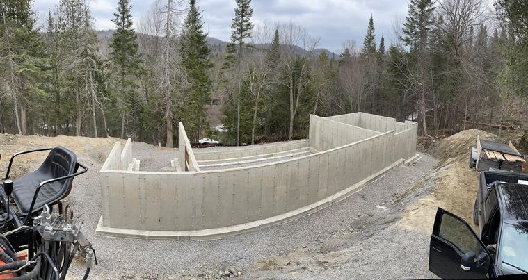 Un grand mur de béton est en construction au milieu d'une forêt.