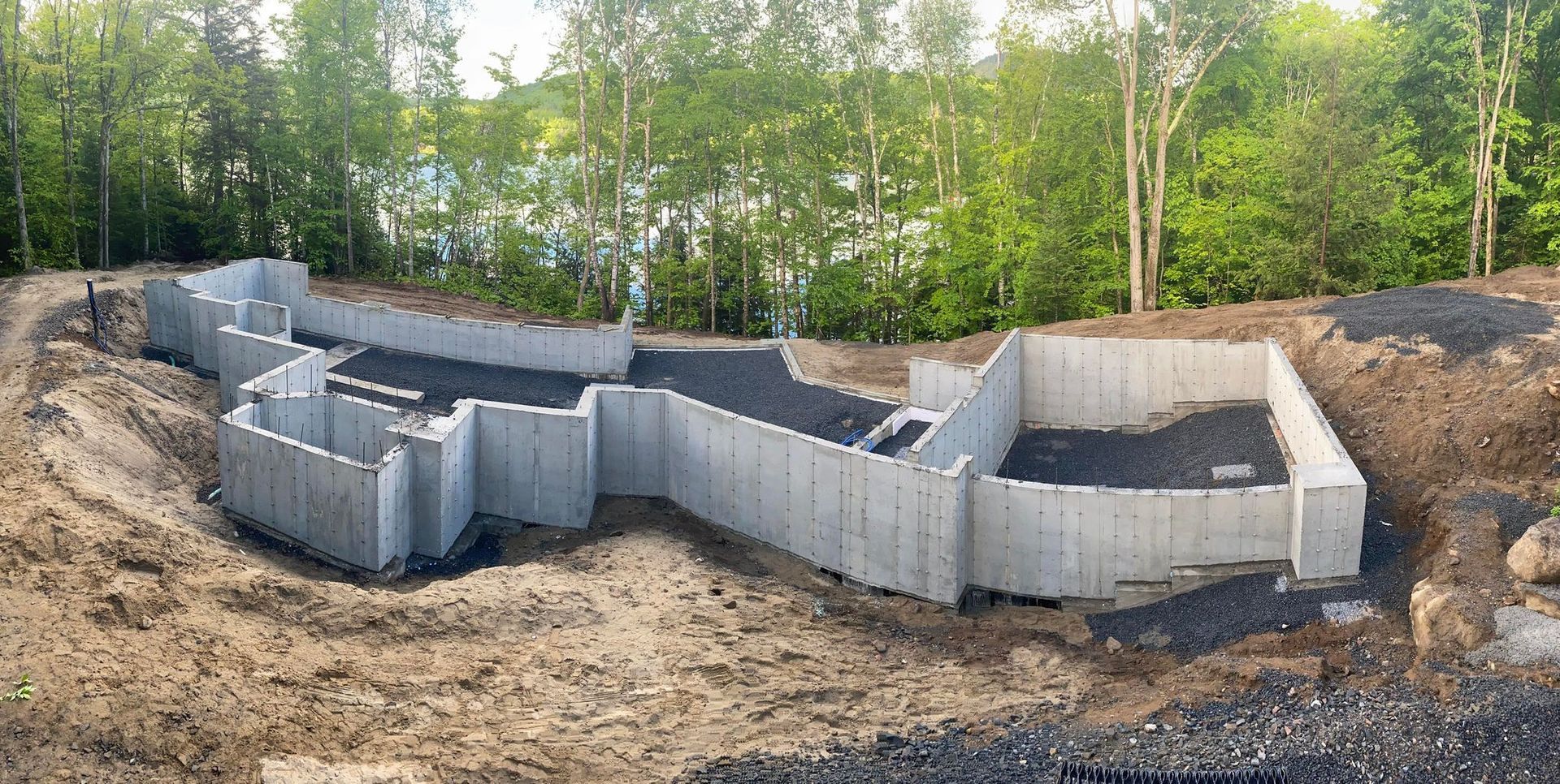 Une grande fondation en béton est en cours de construction au milieu d'une forêt.