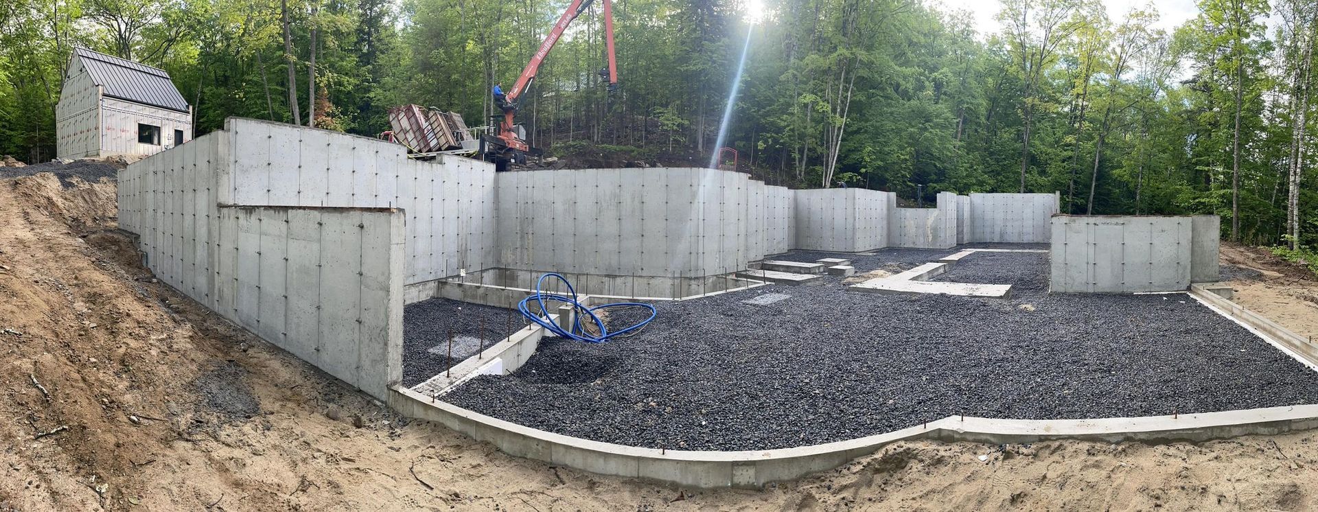 Un grand mur de béton est en cours de construction au milieu d'un champ de terre.