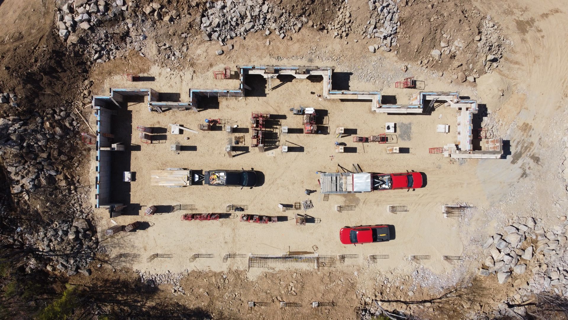 Une vue aérienne d’un chantier de construction avec beaucoup de voitures garées dans la terre.