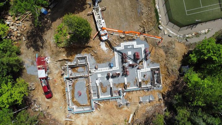 Une vue aérienne d'un chantier de construction avec un court de tennis en arrière-plan.