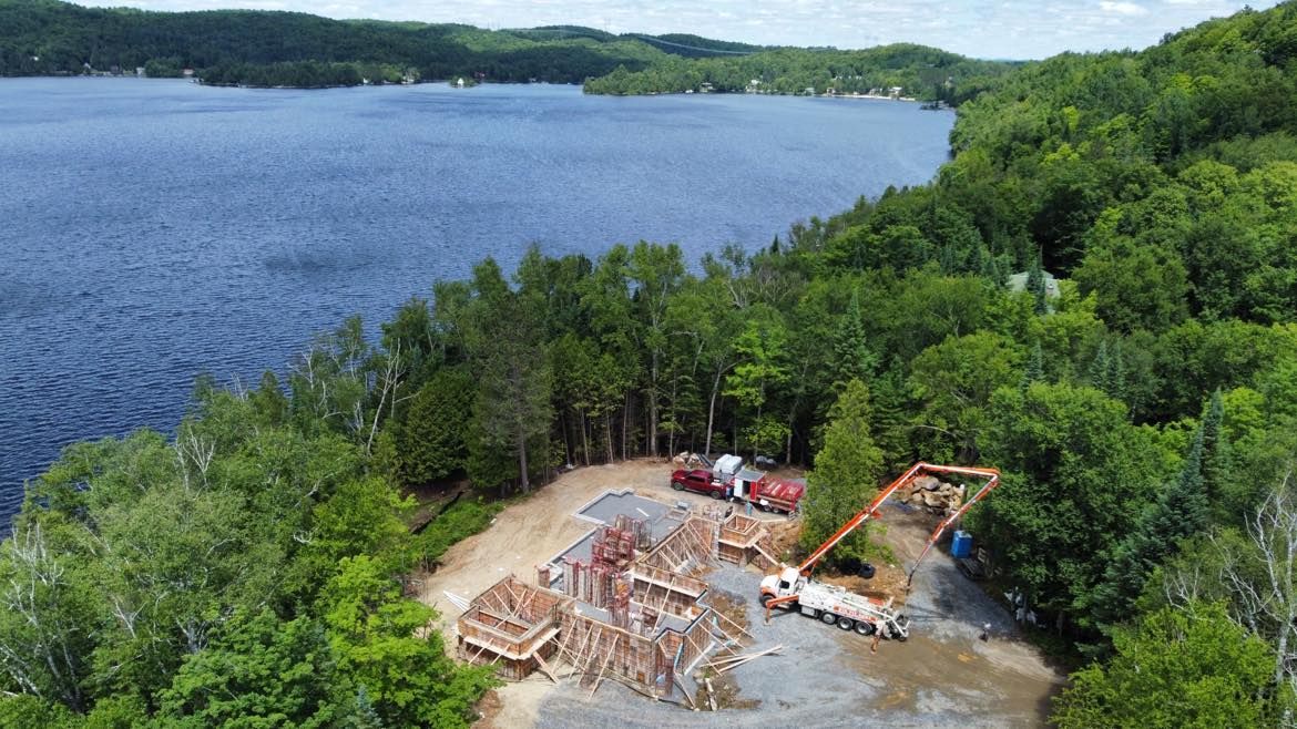 Une vue aérienne d'un chantier de construction au bord d'un lac entouré d'arbres.
