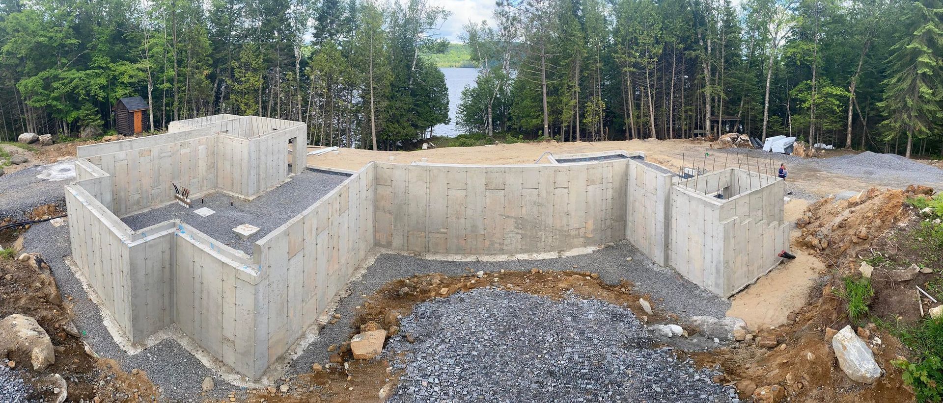 Un grand mur de béton est en cours de construction au milieu d'un champ de terre.