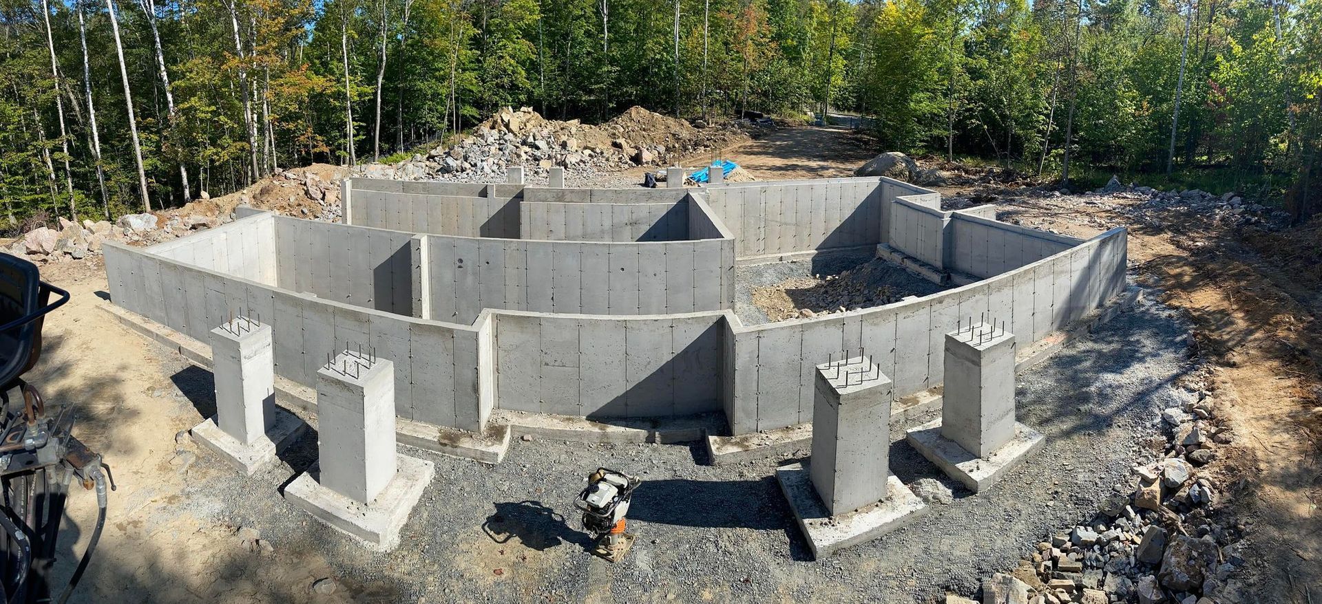 Une grande fondation en béton est en cours de construction au milieu d'une forêt.
