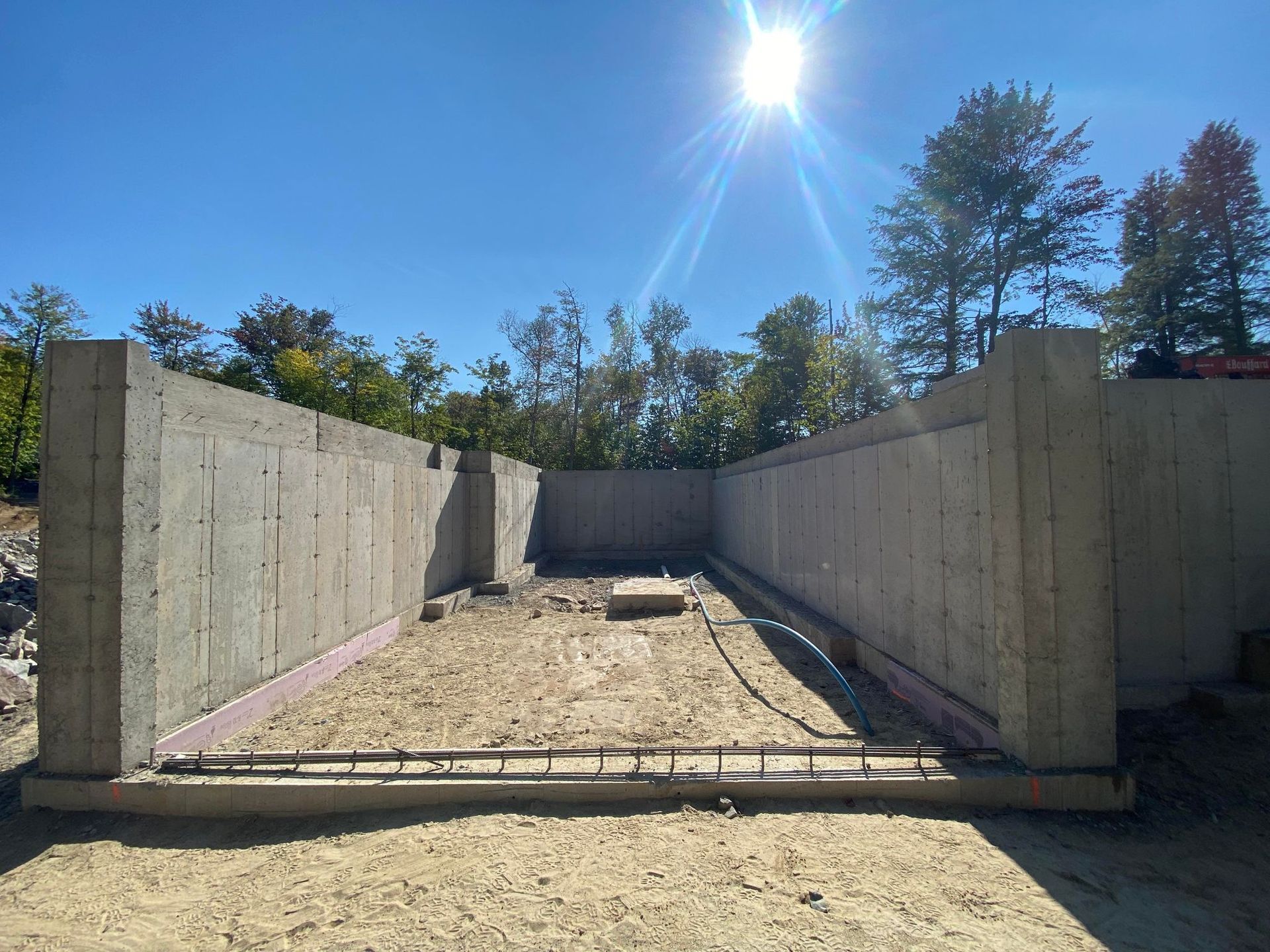 Un grand mur de béton est en cours de construction au milieu d'un champ de terre.