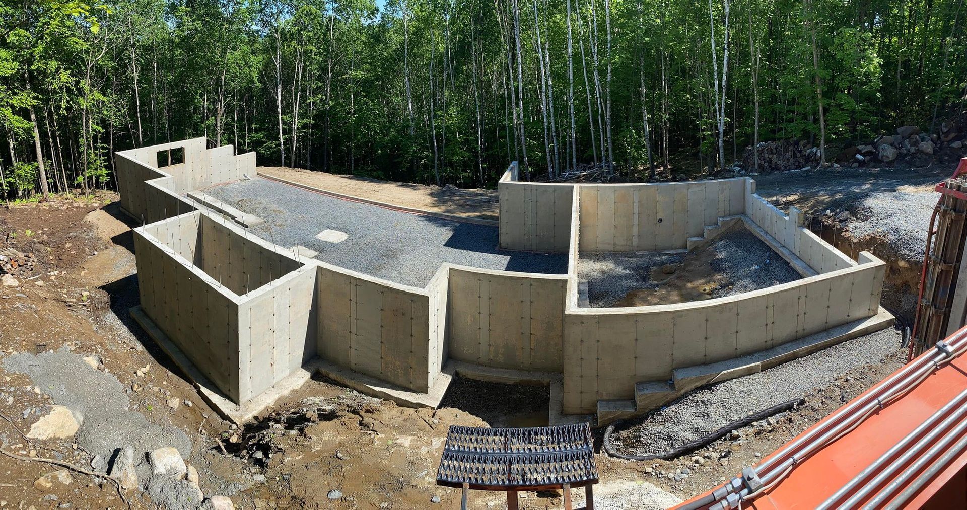 Un grand mur de béton est en construction au milieu d'une forêt.