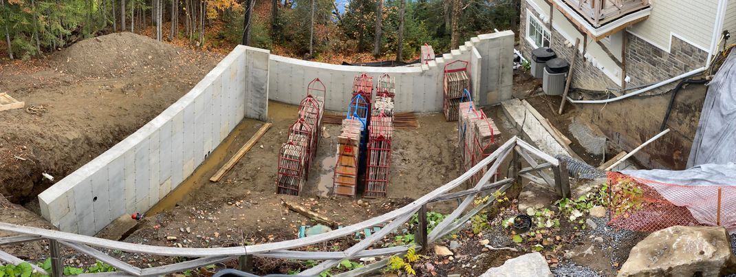 Un grand mur de béton est en cours de construction dans la cour d’une maison.