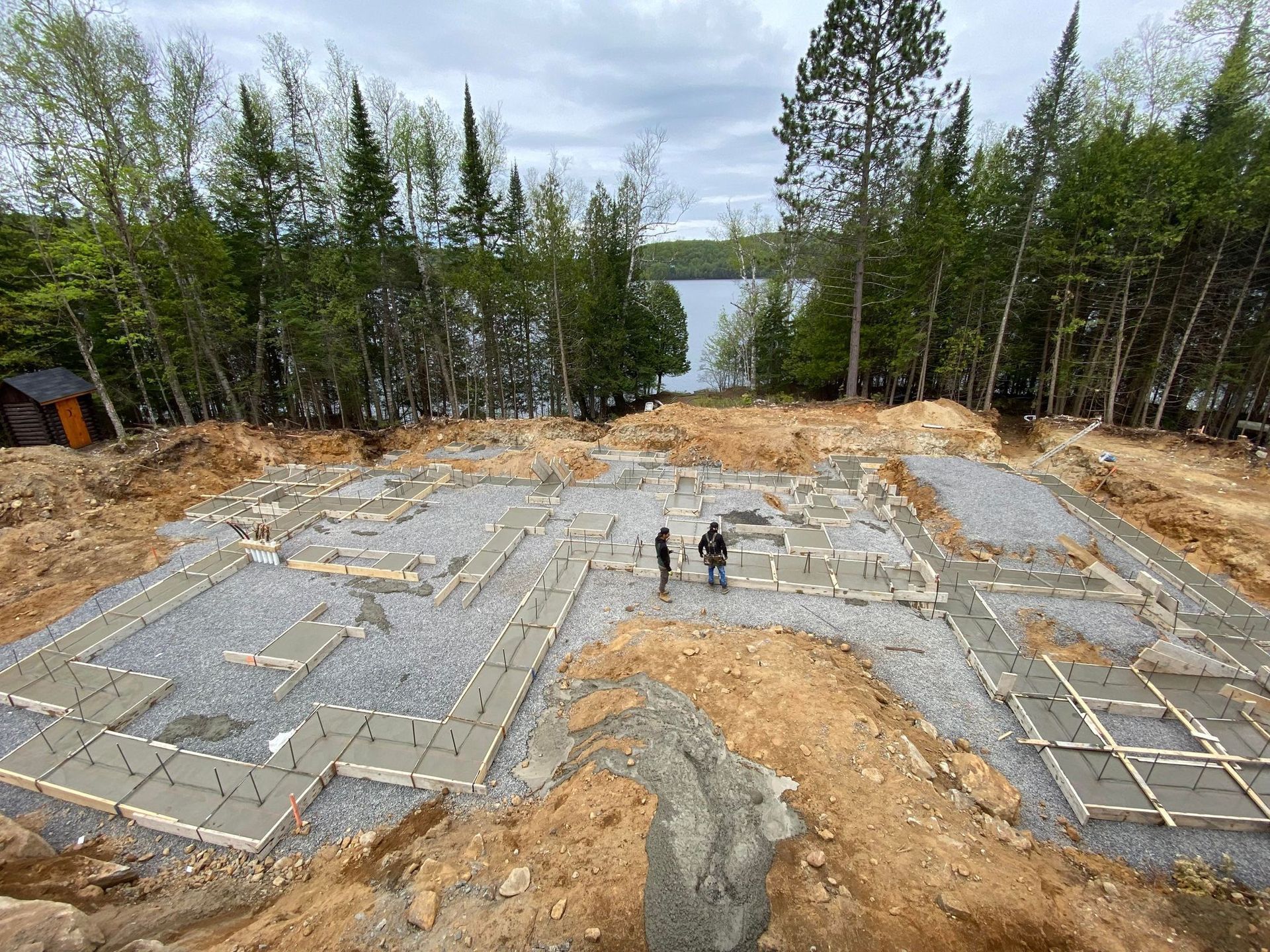 Un couple de personnes debout au sommet d’un champ de terre à côté d’un lac.