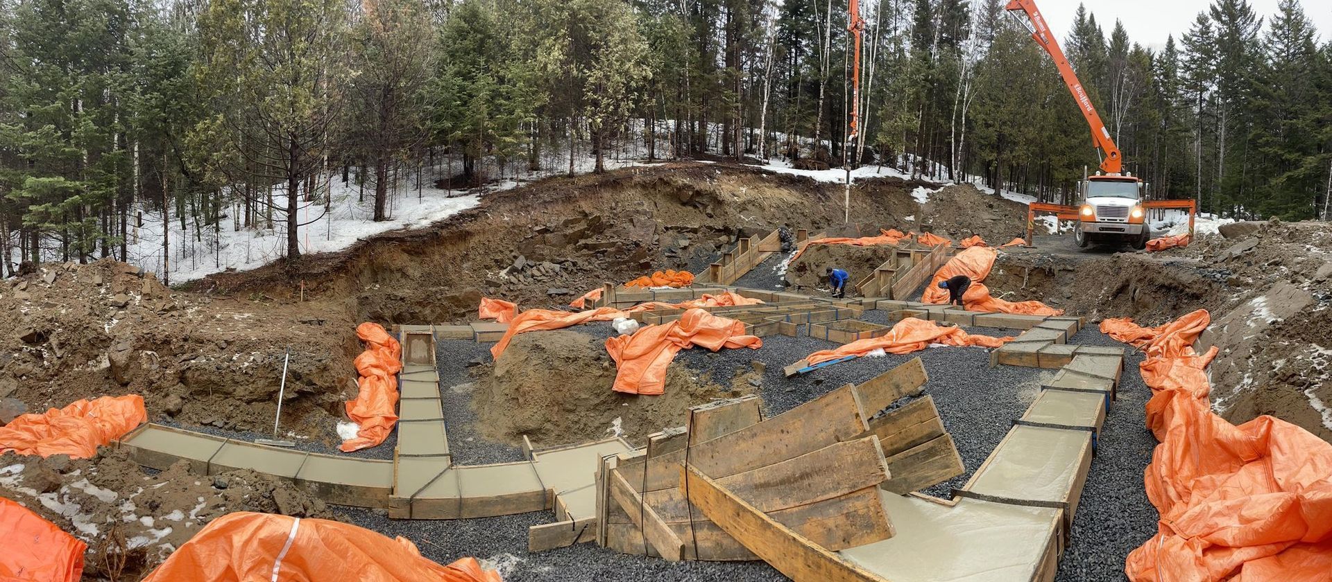 Un chantier de construction avec des bâches orange et une grue en arrière-plan.