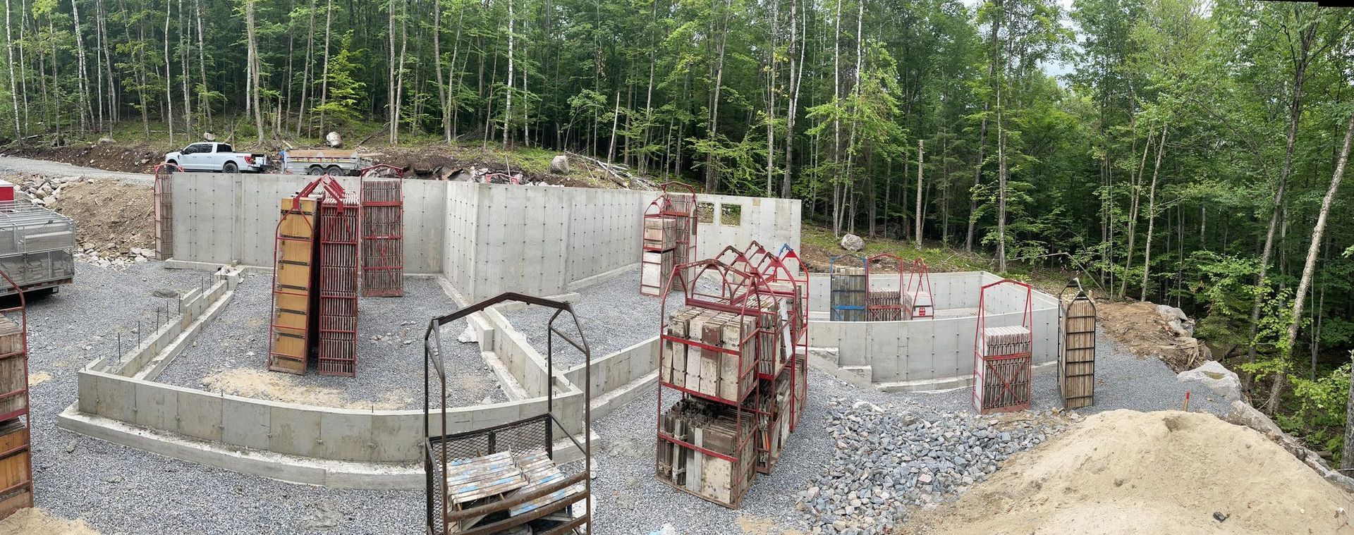 Un grand mur de béton est en construction au milieu d'une forêt.