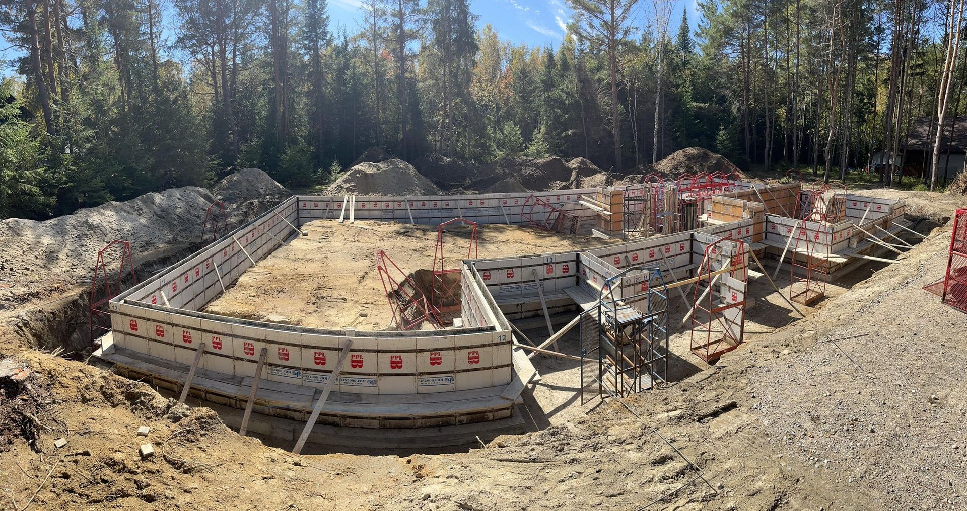 Un chantier de construction avec beaucoup de terre et des arbres en arrière-plan.