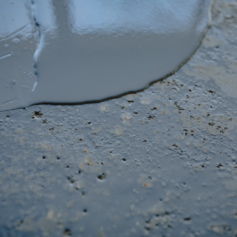 A close up of a concrete surface with a white liquid pouring out of it.