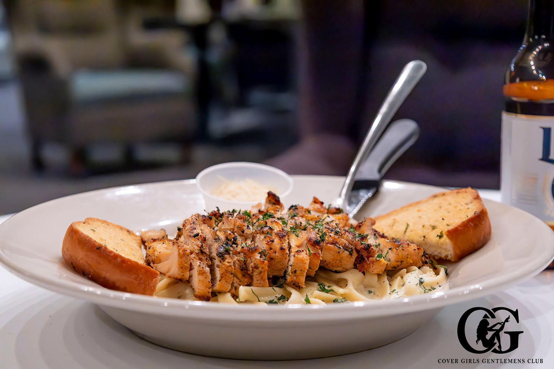A bowl of alfredo pasta with chicken and garlic bread