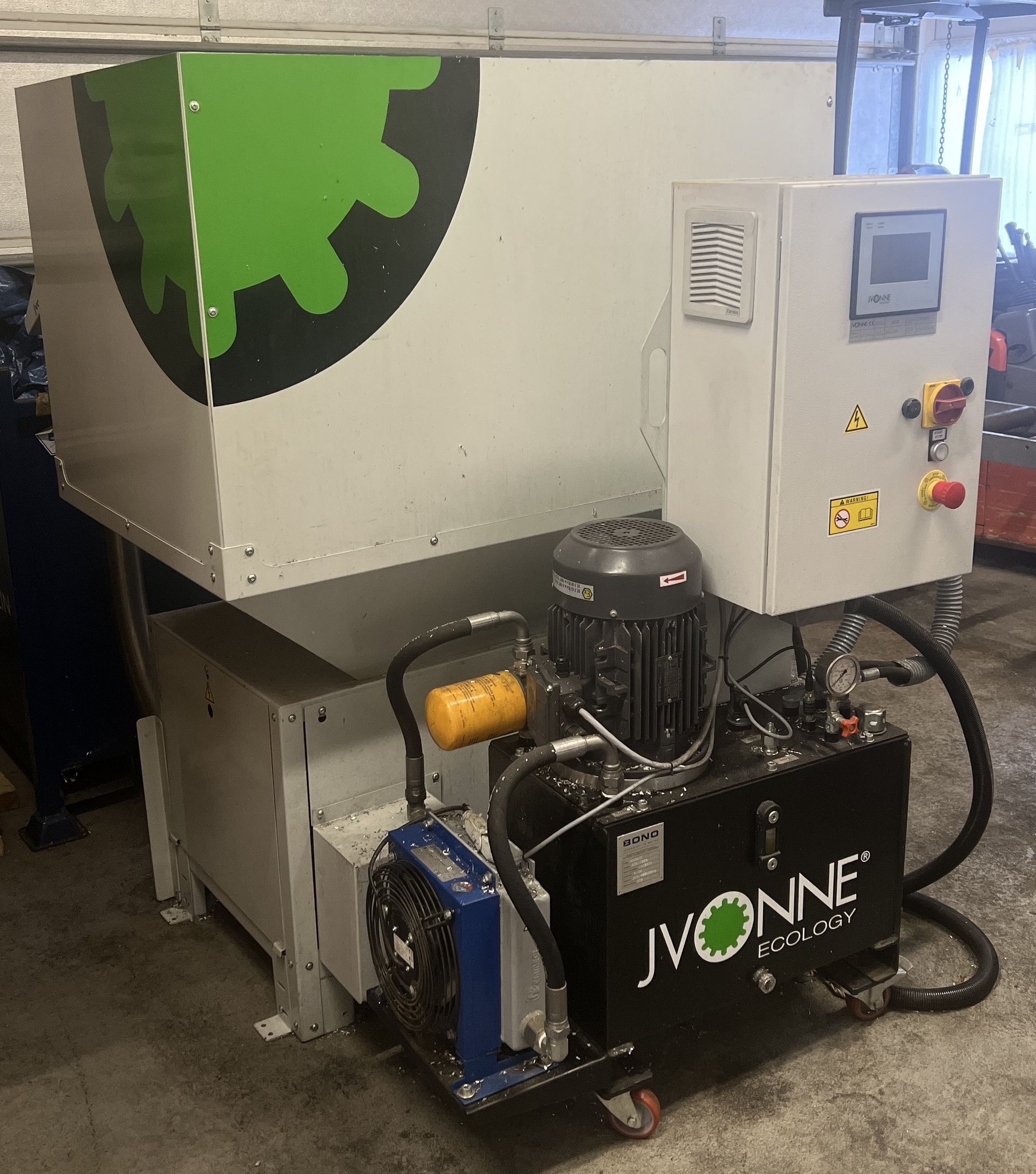 Industrial shredder with a gray hopper, a black hydraulic motor unit labeled 