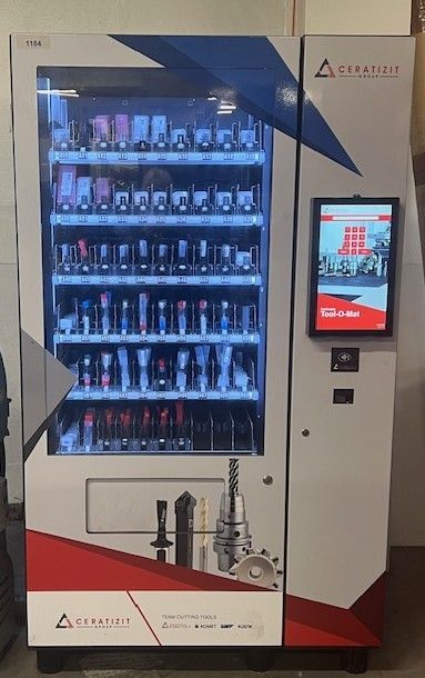 A white, red, and blue industrial vending machine for tools with a glass front, shelves, and a digital touchscreen.