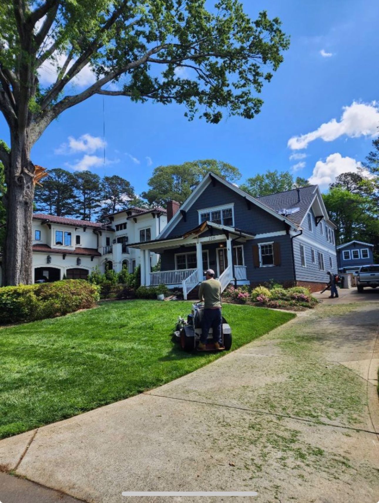 A man is mowing the lawn in front of a house