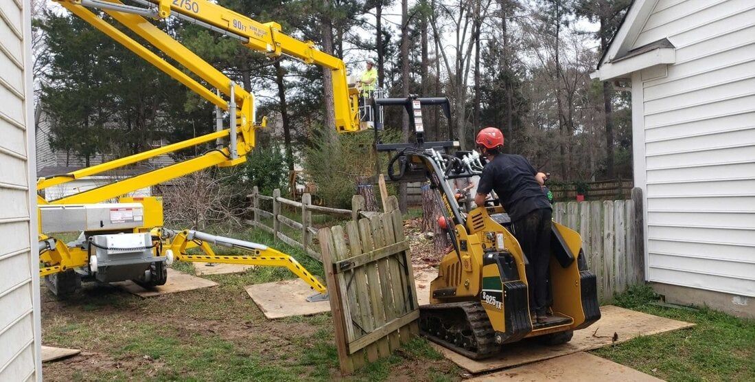 A man is using a machine to remove a tree from a fence.