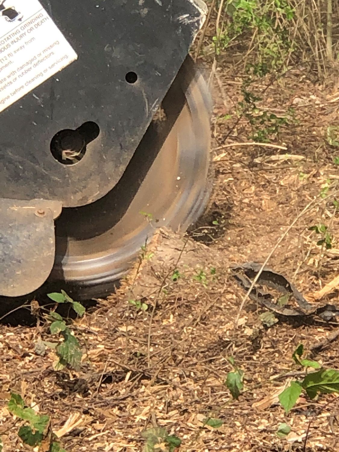 A circular saw is cutting a tree stump in the dirt.