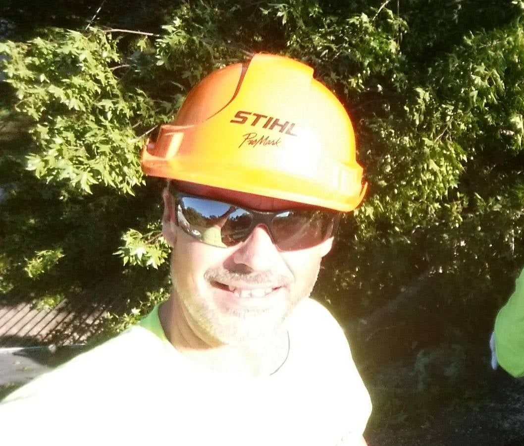 A man wearing a stihl hard hat and sunglasses