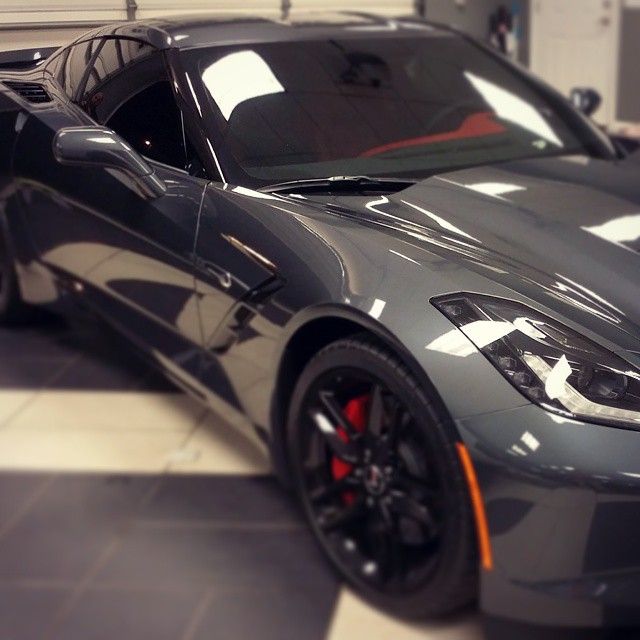 Gray Chevrolet Corvette sports car with black wheels and red brake calipers.