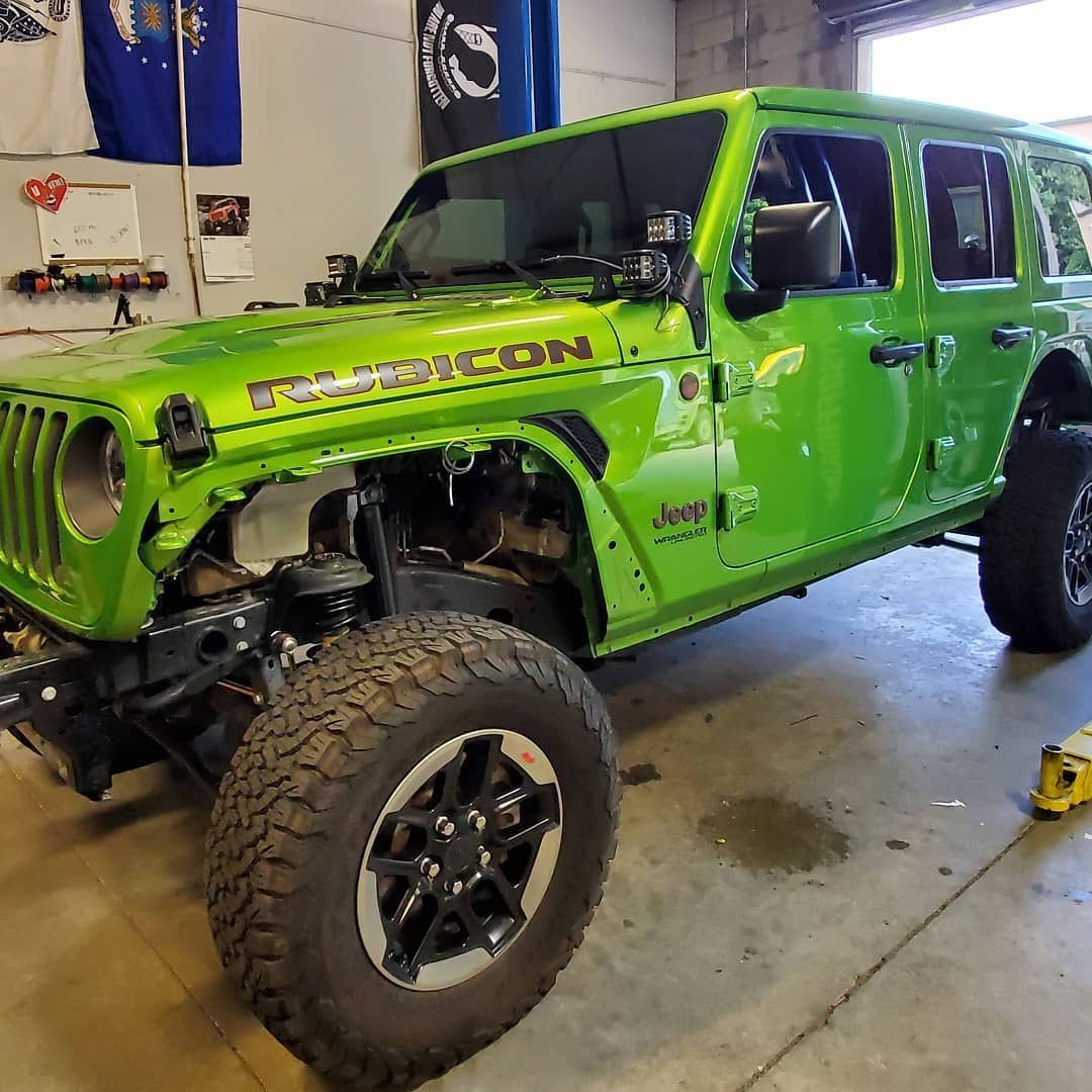 Bright green Jeep Wrangler Rubicon, partially disassembled in a workshop.
