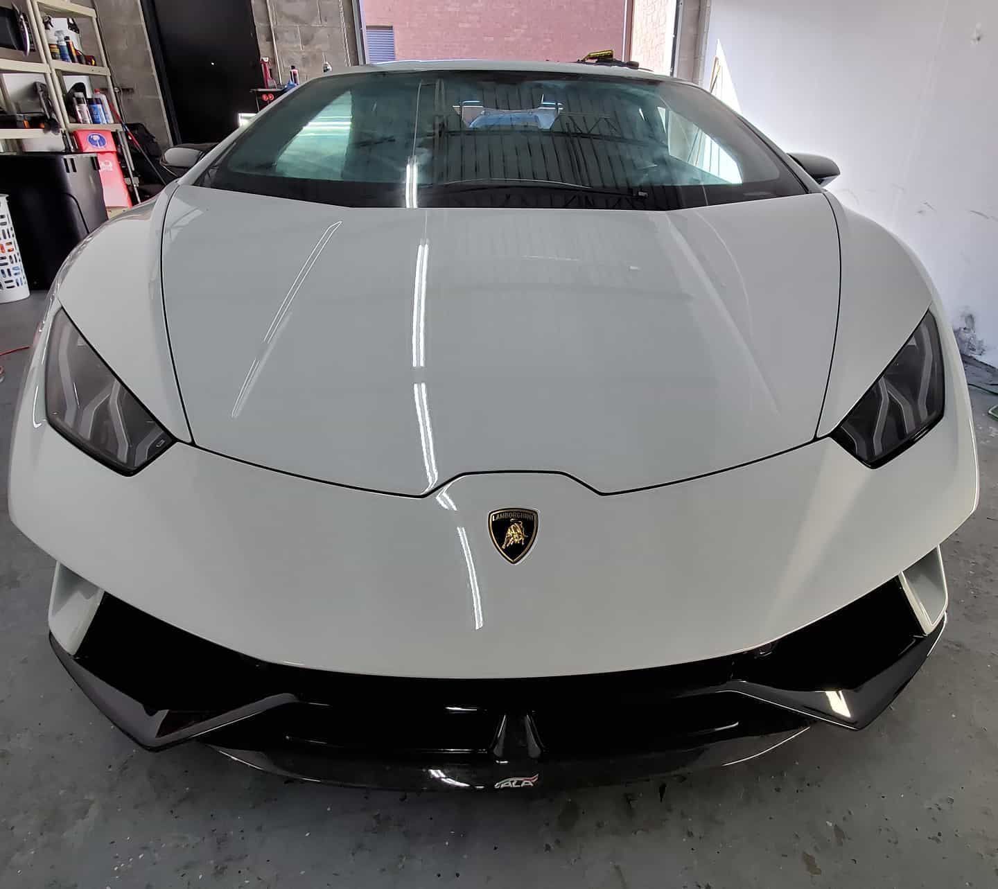 White Lamborghini Huracán sports car, front view, in a garage.