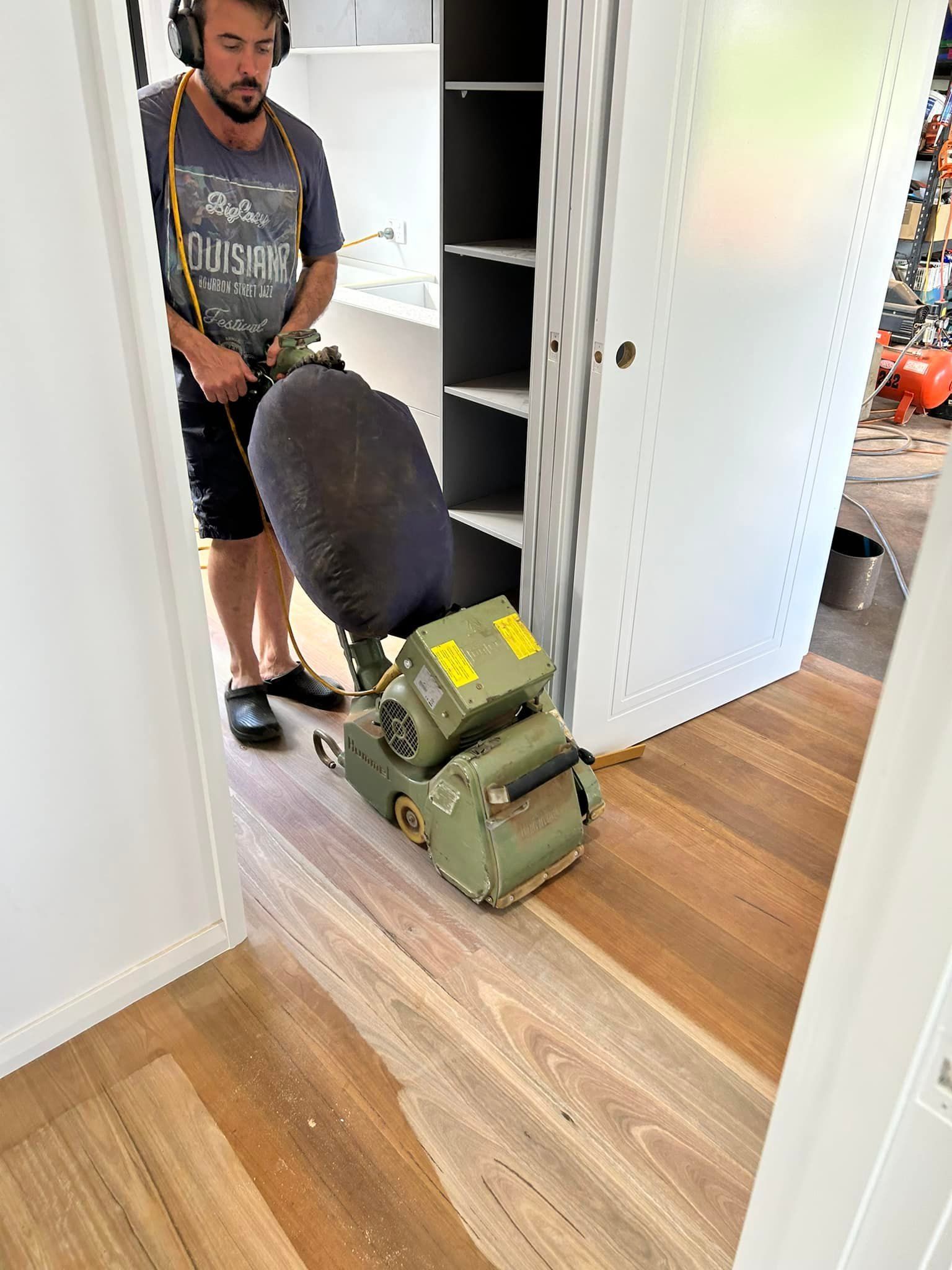 Man Using A Floor Sander On Wood Planks Inside A Room — Scott Johnston Floor Sanding in Mareeba, QLD
