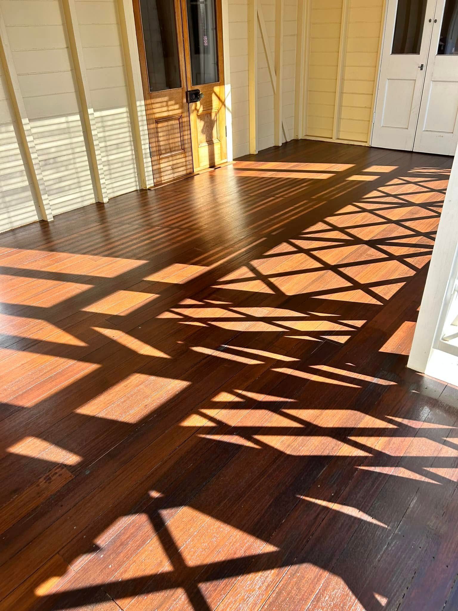 Wooden Porch Floor With Geometric Shadows From A Latticed Railing — Scott Johnston Floor Sanding in Bentley Park, QLD