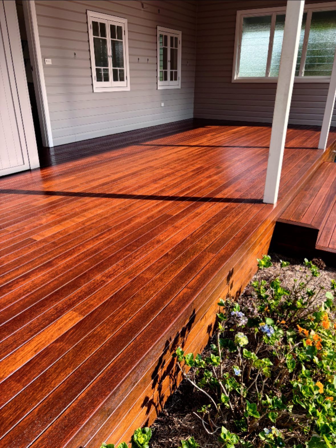 Newly Stained Red-brown Wooden Deck On A House Porch — Scott Johnston Floor Sanding in Bentley Park, QLD
