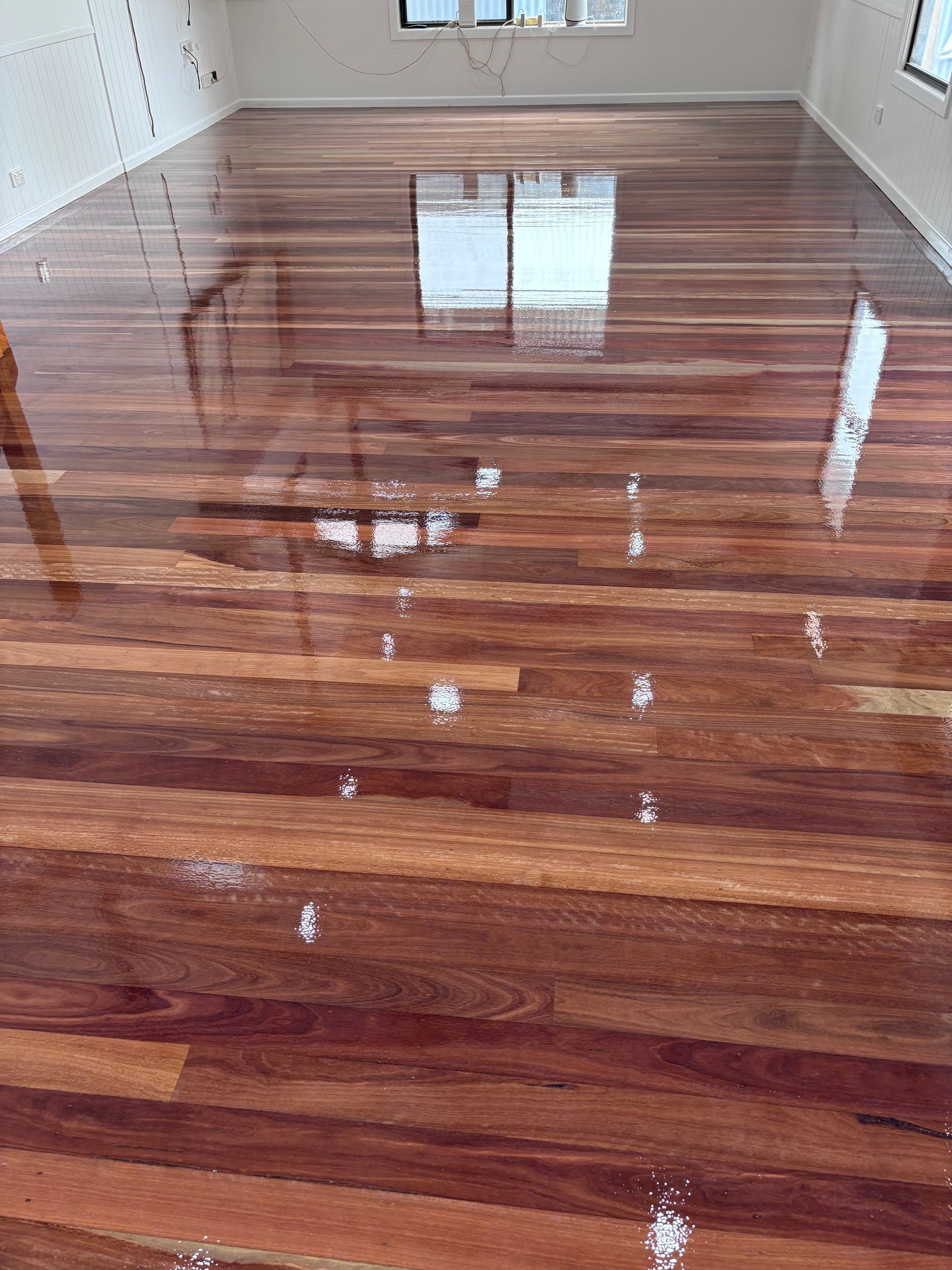Glossy Wooden Floor Reflecting Natural Light — Scott Johnston Floor Sanding in Bentley Park QLD
