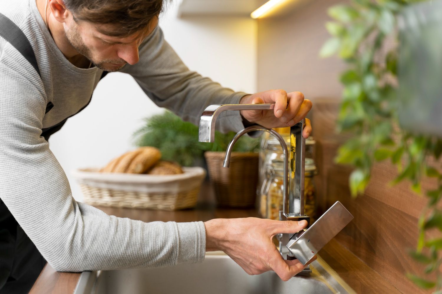 A man is fixing a faucet in a kitchen.