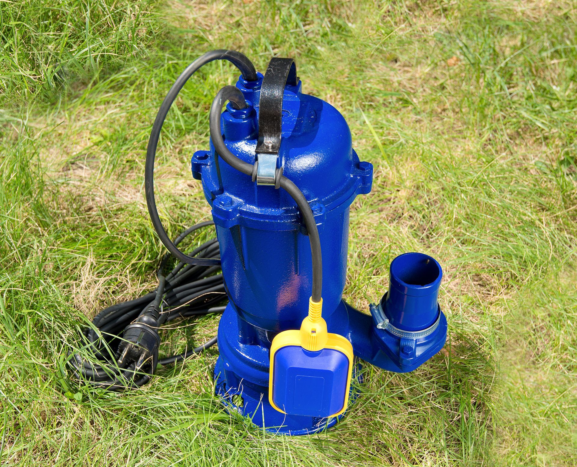 A blue water pump is sitting on top of a lush green field.