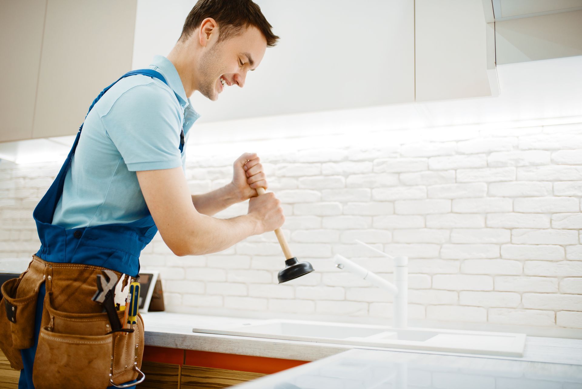 A man is using a plunger to fix a sink.