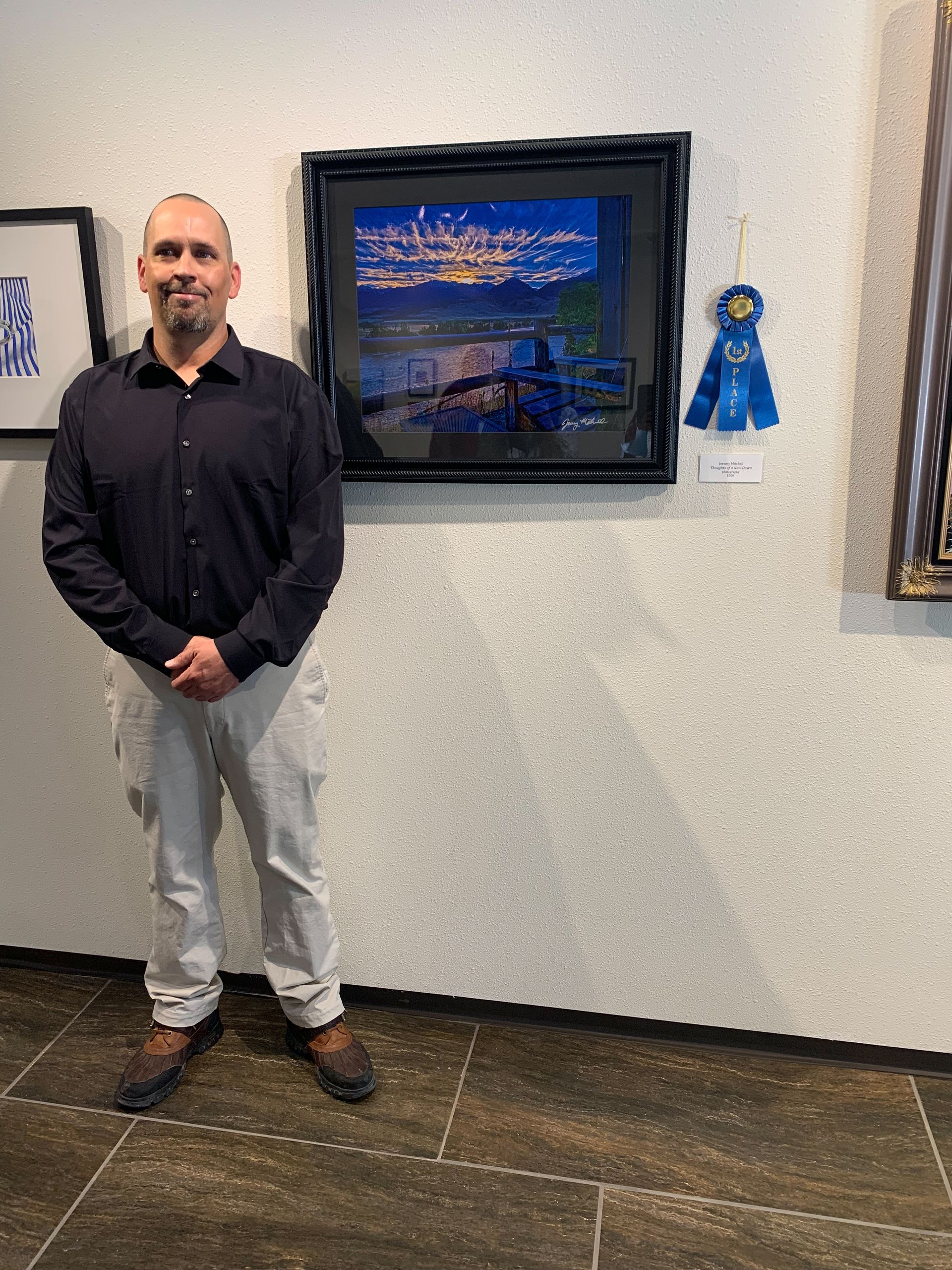 A man is standing in front of a painting on a wall.