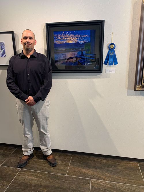 A man is standing in front of a painting on a wall.