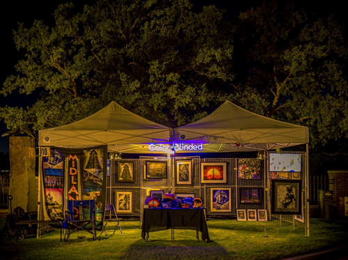 A tent with paintings on it is lit up at night.
